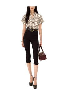 A woman wears a chloé women’s beige top with black polka dots short flutter sleeves and a ruffled collar