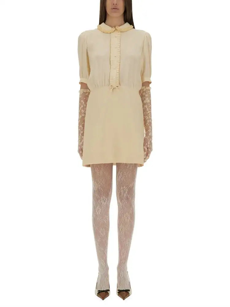 A creamy off-white, short-sleeved dress with a peter pan collar and lace-trimmed cuffs.
