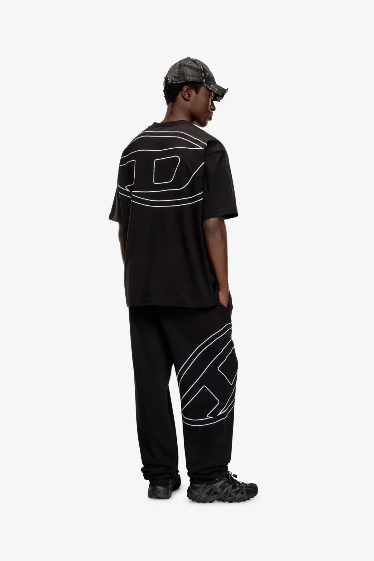 Back view of diesel men’s boggy black cotton t shirt with bold white geometric line art on shirt and pants side
