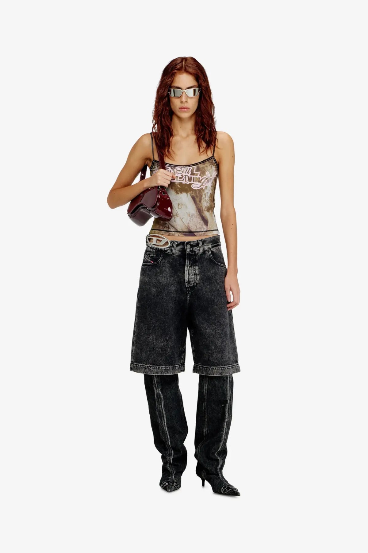 A glossy burgundy leather handbag with a rounded shape and metallic logo paired with diesel black denim bermuda shorts