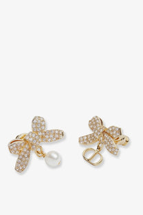 Dior women’s gold metal bow earrings with sparkling crystals, a dangling pearl, and Dior logo charm on each side