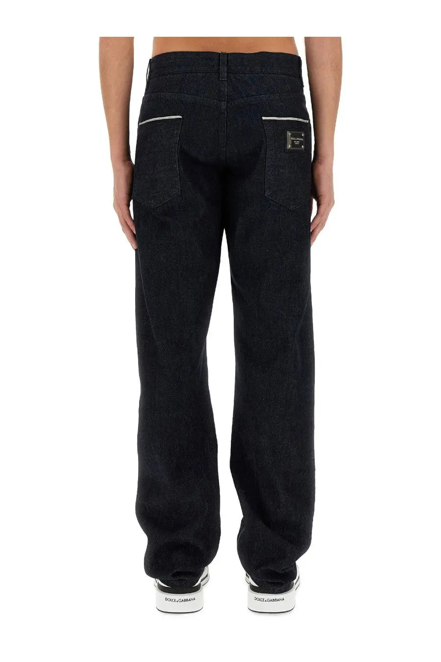 Back side of dolce &amp; gabbana men’s cimosed black denim jeans with white stitching and metallic brand patch on pocket