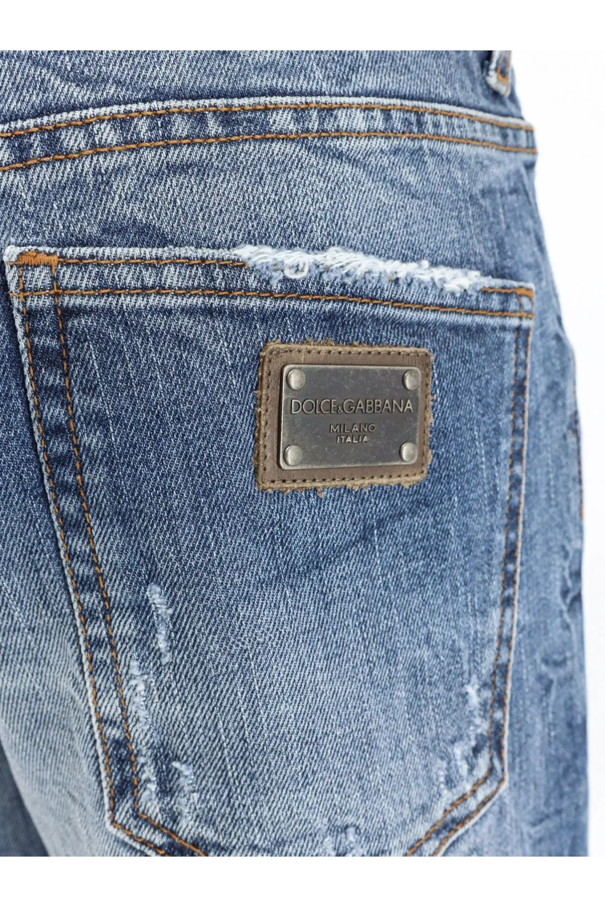 Back side of blue cotton denim dolce and gabbana men’s jeans with distressed frayed pocket and brown leather patch