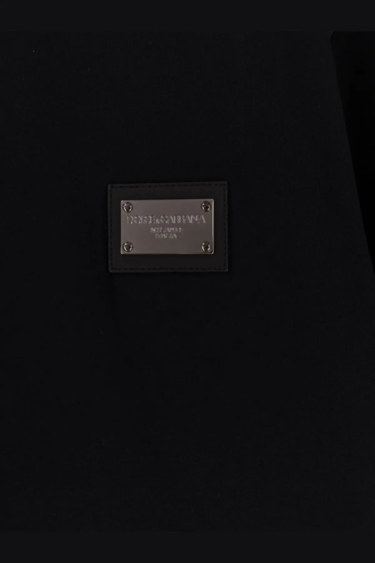 Black leather dolce &amp; gabbana label with silver metal plate and screws on the back of a men’s black cotton shirt