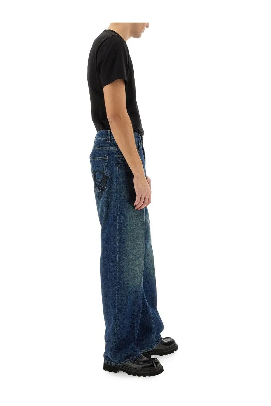 Back side of dolce &amp; gabbana men’s oversize blue denim jeans with a black skull patch on the back pocket