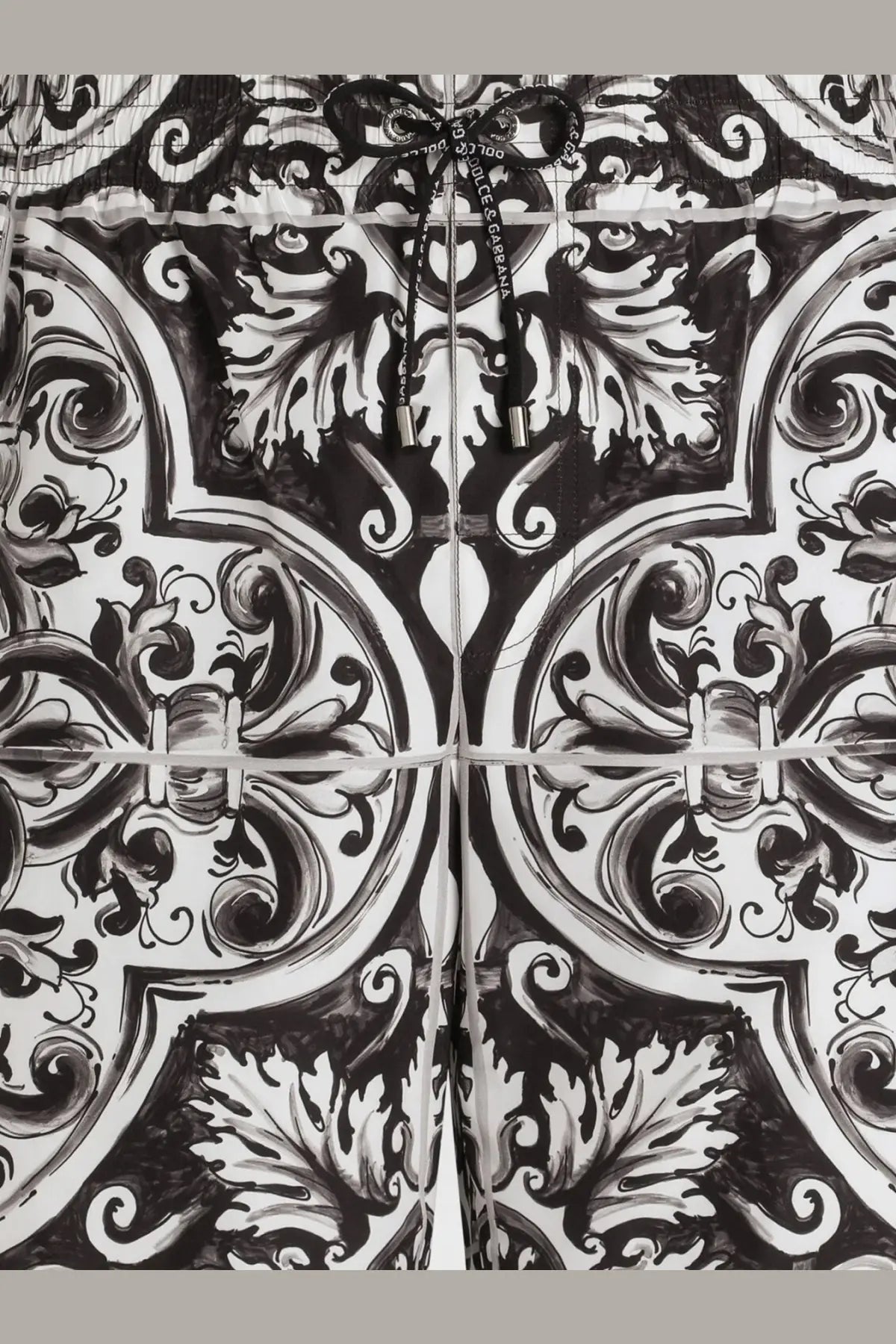 Black and white ornate patterned hoodie with drawstring closure paired with dolce and gabbana men’s swim trunks black