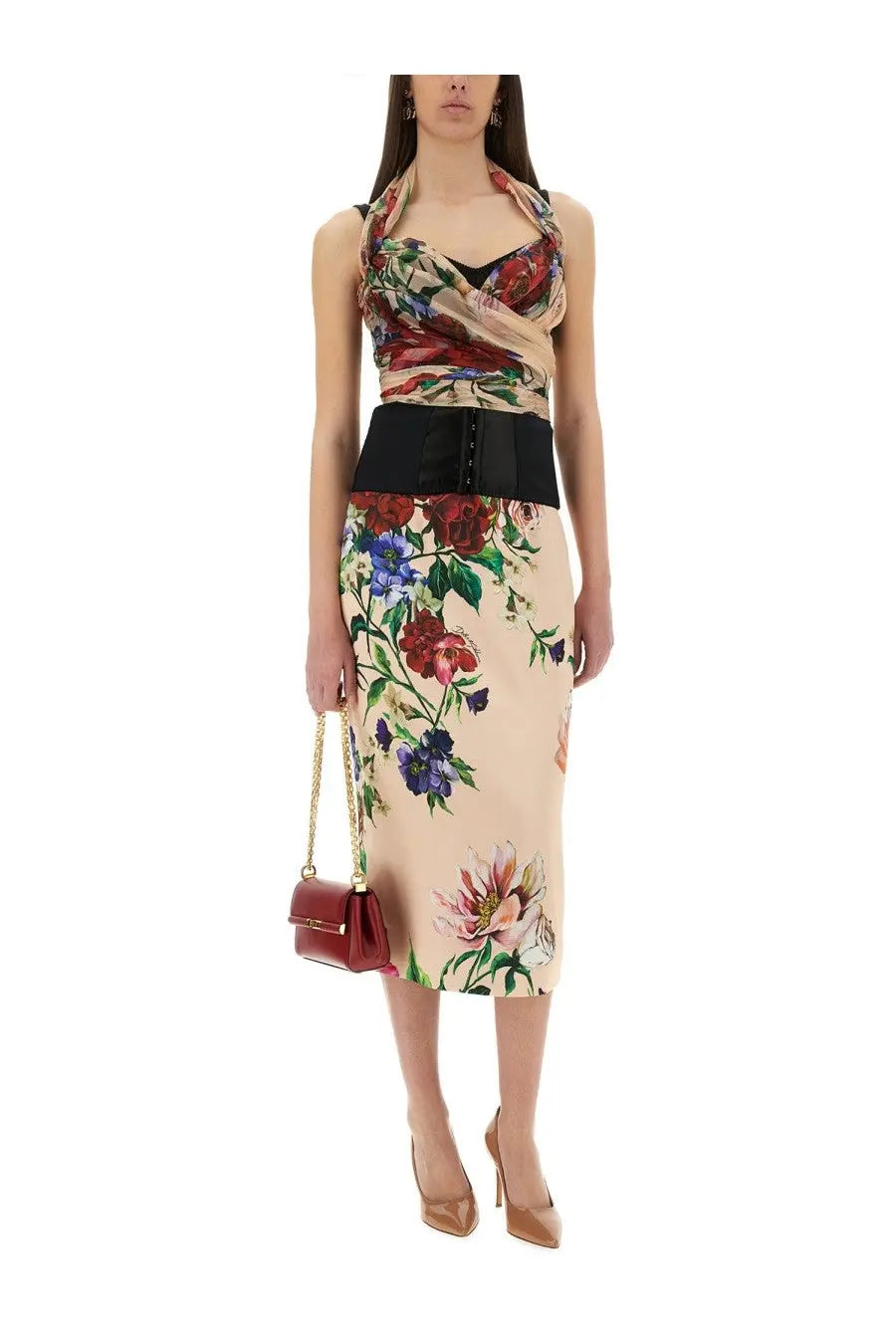 A woman wearing a Dolce &amp; Gabbana blue flower print satin midi pencil skirt with a black corset belt and red handbag