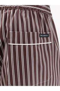 Brown and white vertically striped swim trunks with a elastic waistband, featuring a front pocket adorned with the dolce &amp; gabbana brand label.
