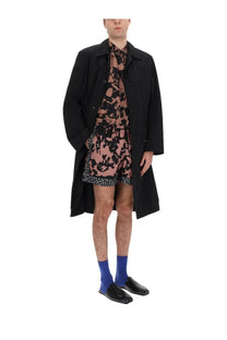 Dries Van Noten men’s rankles black trench coat with classic collar and button closure over pink floral dress