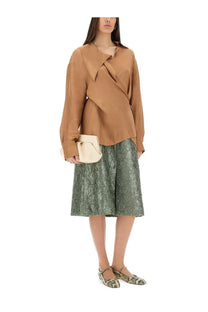 A beige structured clutch with a soft minimalist design paired with a green ruched satin midi skirt by dries van noten