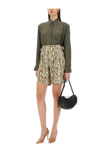 Black leather crescent-shaped handbag with short handle and decorative tassels shown with dries van noten green silk blend satin shirt
