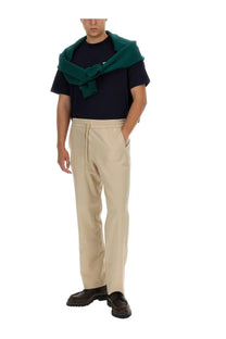 Beige drawstring cotton trousers with relaxed fit and subtle creases paired with drôle de monsieur blue shirt
