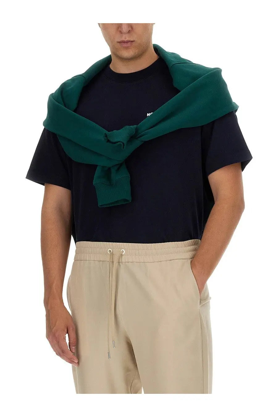 Dark green knitted sweater draped over shoulders with drôle de monsieur men’s blue cotton shirt visible underneath