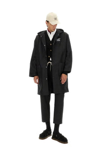 Drôle de Monsieur men’s black hooded parka with white button accents and drawstring waistband in trench coat style