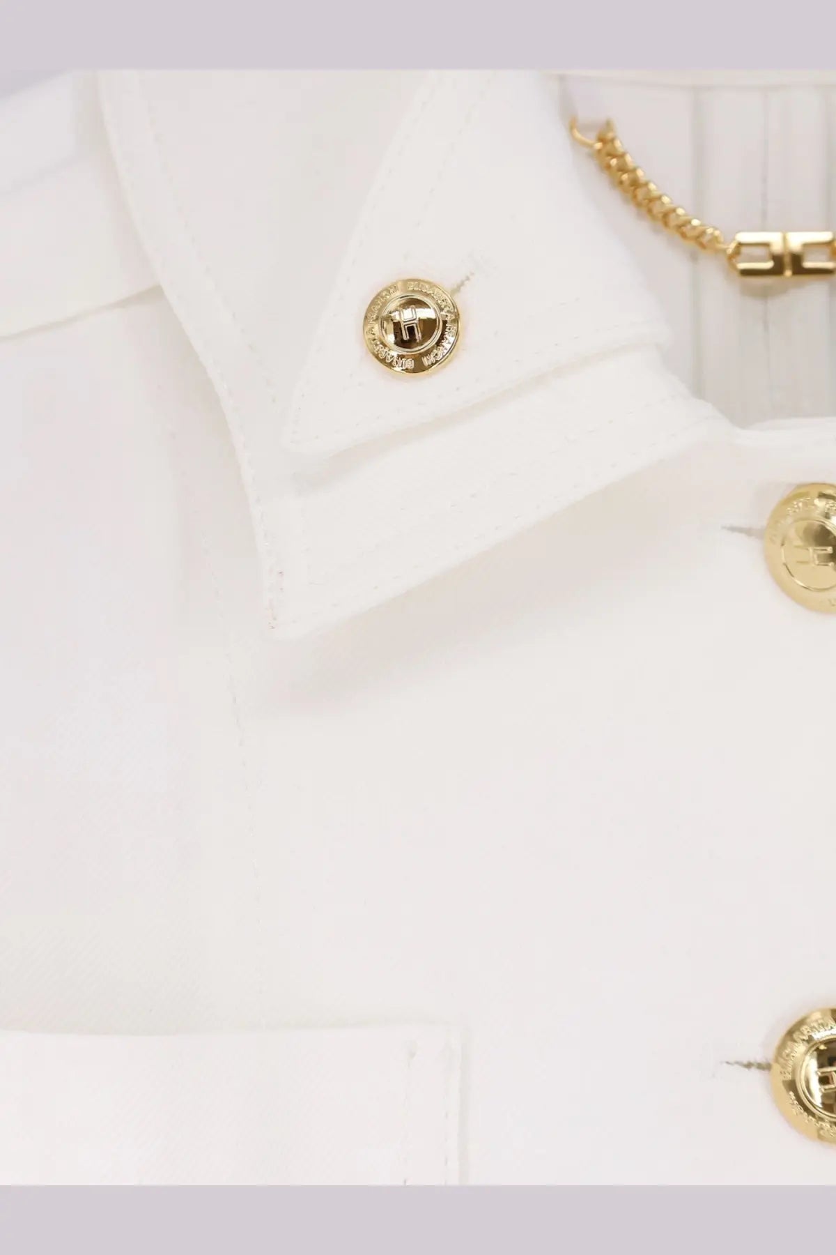 Gold-toned circular cufflinks with raised logo attached to white shirt collar in elisabetta franchi women’s cropped viscose jacket