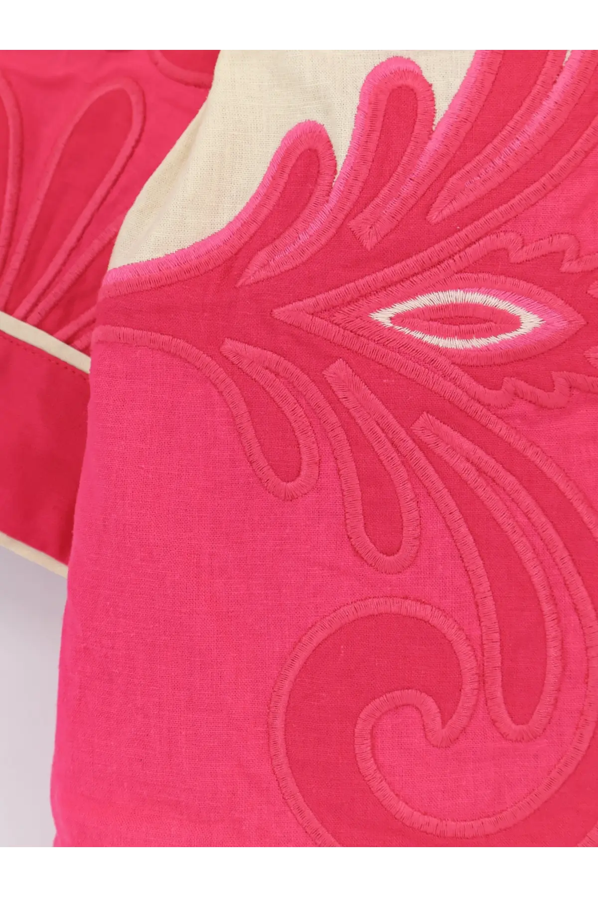 A vibrant pink embroidered cushion with cream border shown alongside farm rio women’s blue linen and viscose kimono