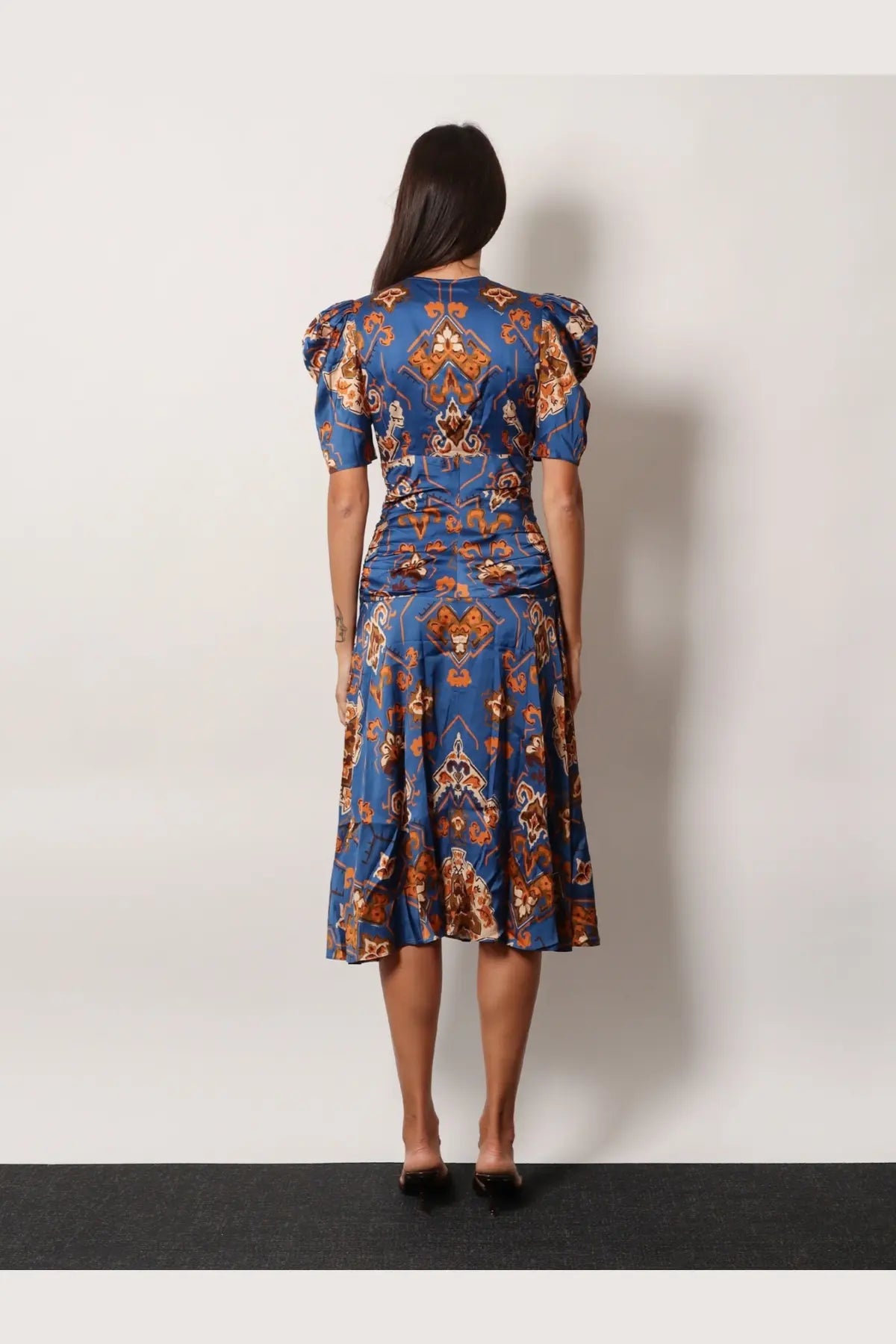A woman wears a farm rio women’s ornament floral viscose midi dress blue with orange brown geometric pattern and puffed sleeves