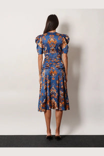 A woman wears a farm rio women’s ornament floral viscose midi dress blue with orange brown geometric pattern and puffed sleeves
