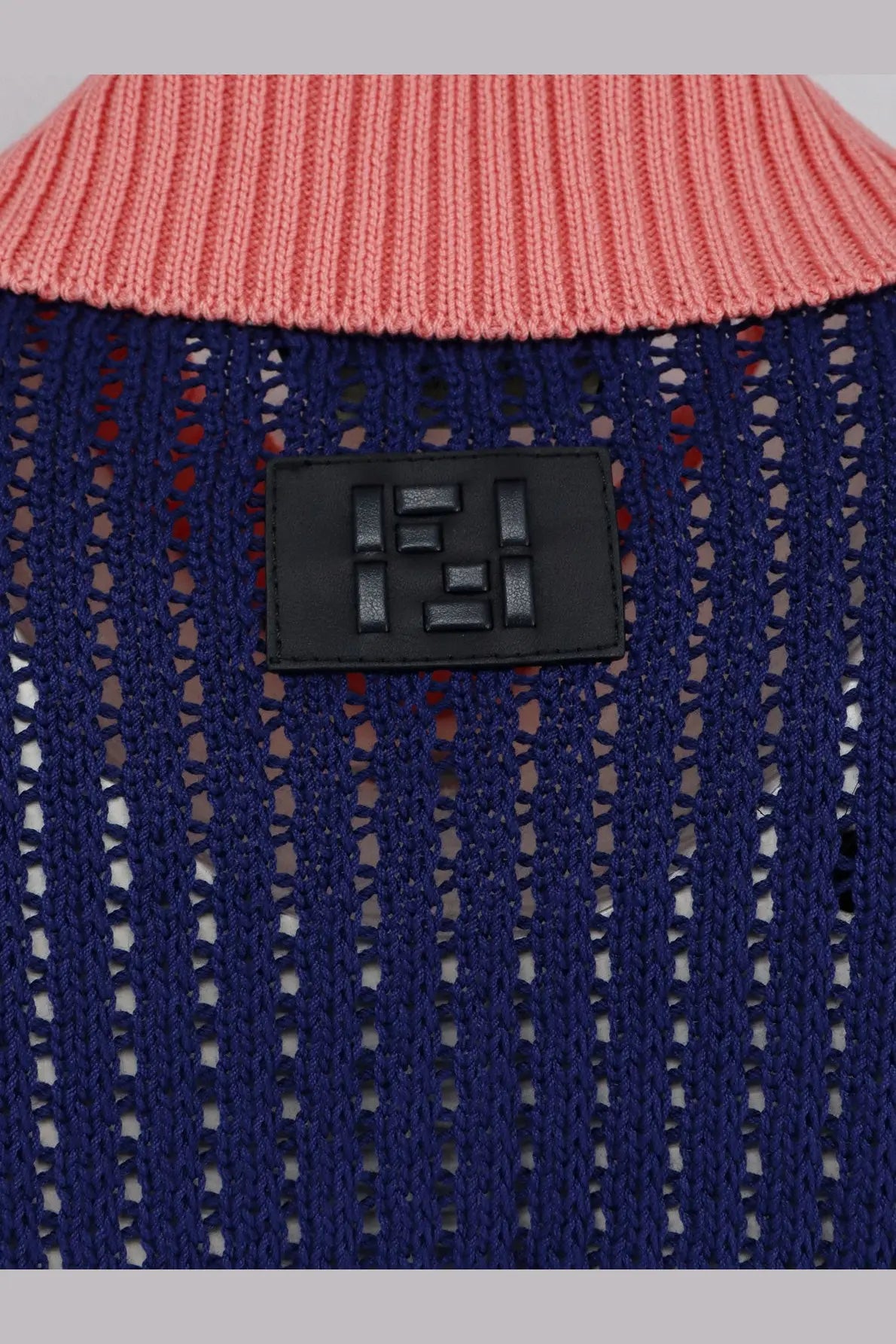 A navy blue knitted cotton sweater with a pink ribbed collar and black leather patch featuring the Fendi logo