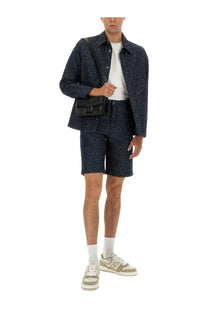 Black crossbody bag with structured rectangular shape and prominent front buckle closure paired with Fendi men’s blue denim shirt