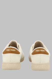 Cream-colored canvas fred perry men’s tennis shoes with tan leather heel tabs and gold logo detailing