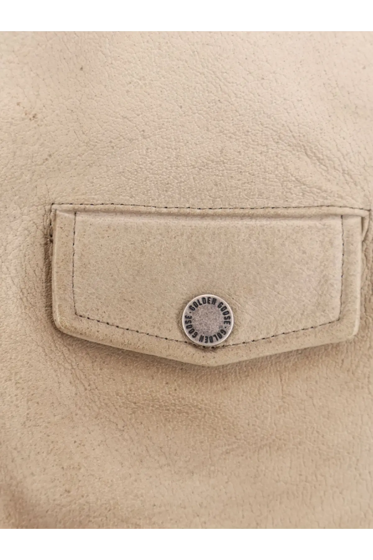 Beige leather pocket with silver circular button featuring golden goose logo on golden goose men’s phoebe leather jacket