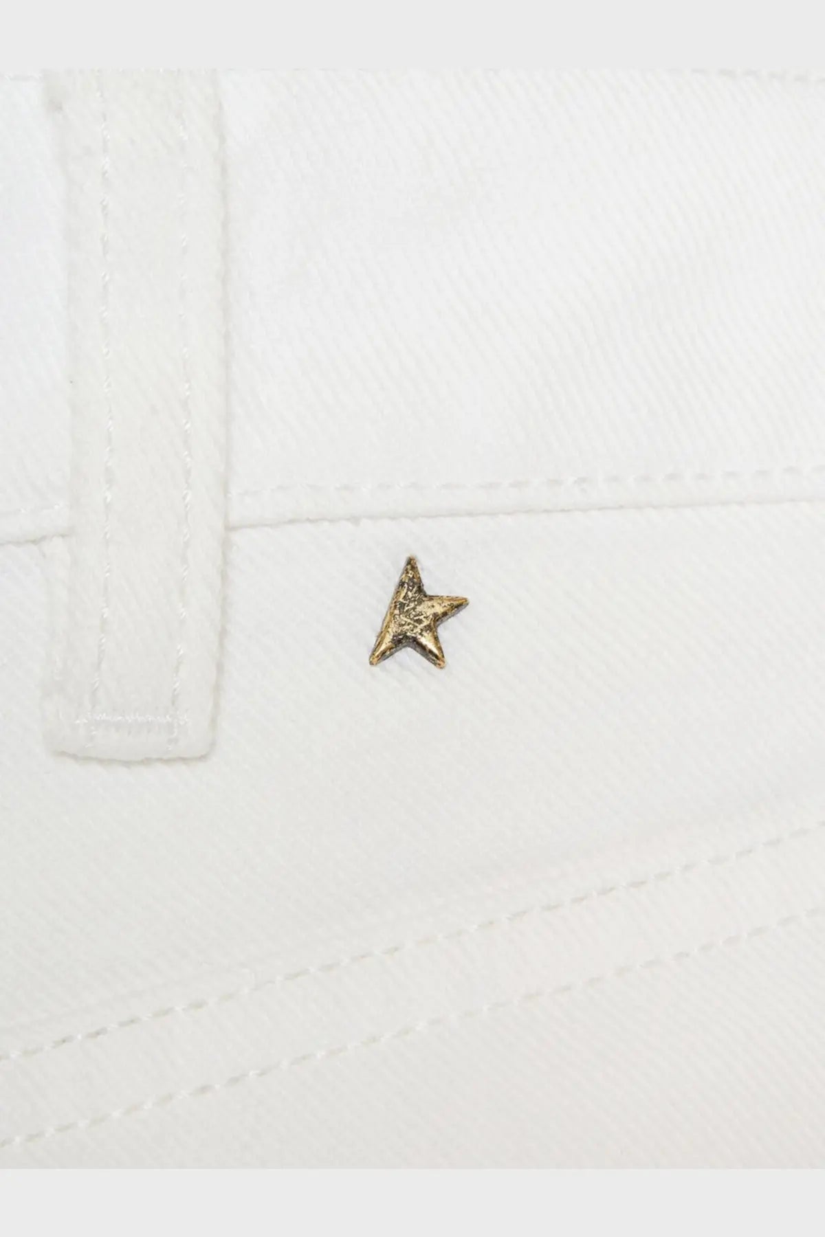 A small textured gold star pin on white fabric detail of golden goose women’s denim trousers white