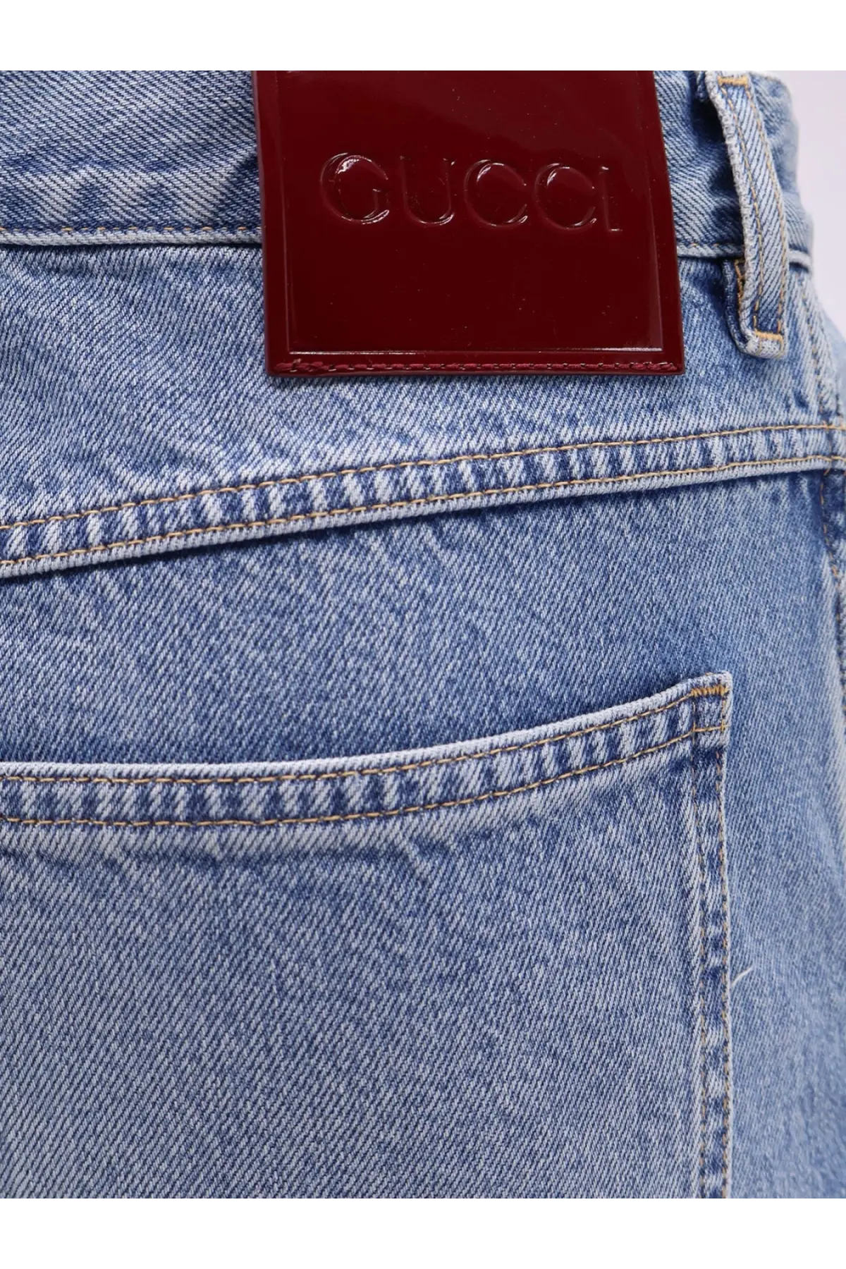 A glossy burgundy leather patch with embossed gucci logo on the back of light-wash gucci men’s slim fit denim jeans