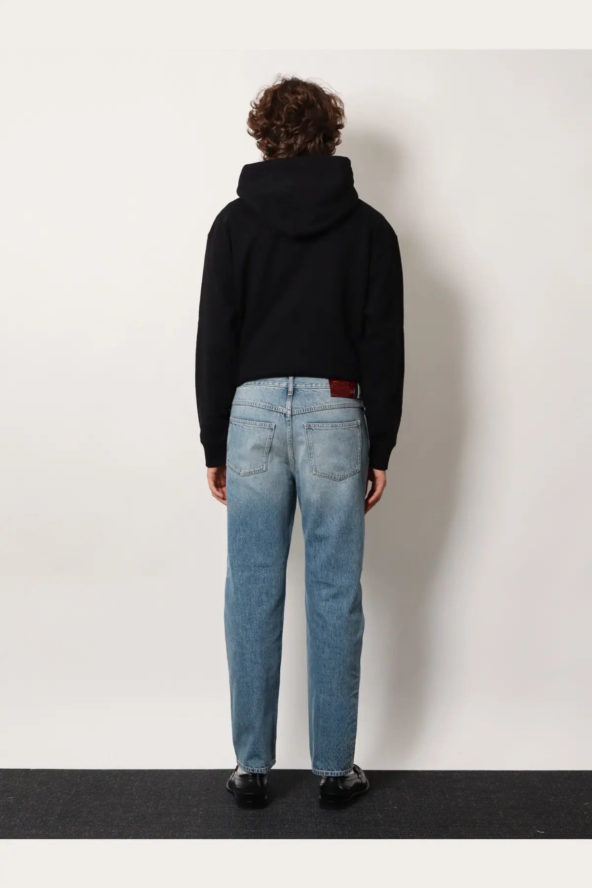 Gucci men’s certified cotton slim fit light-wash denim jeans with straight-leg cut and red leather patch at waistband