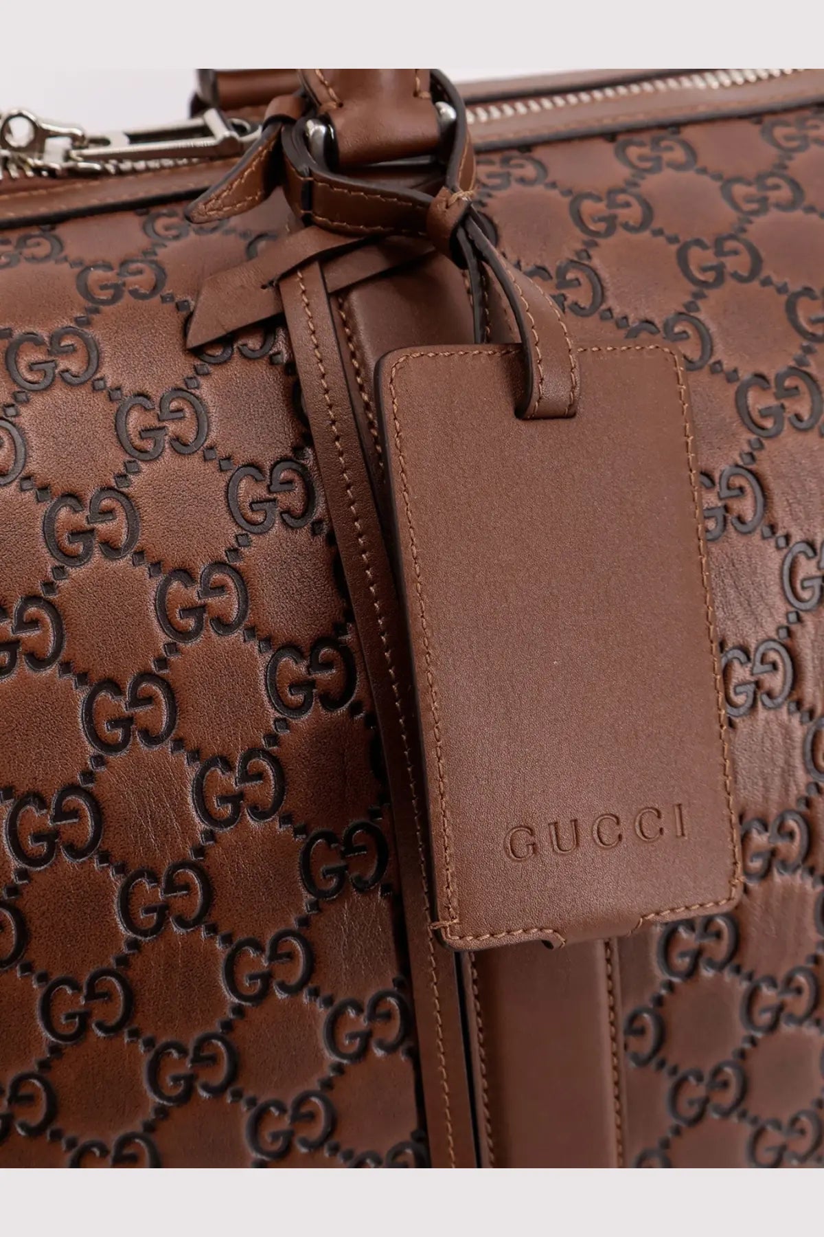 Brown leather gucci luggage tag with embossed gg logo pattern on gucci men’s gg emblem duffle bag black
