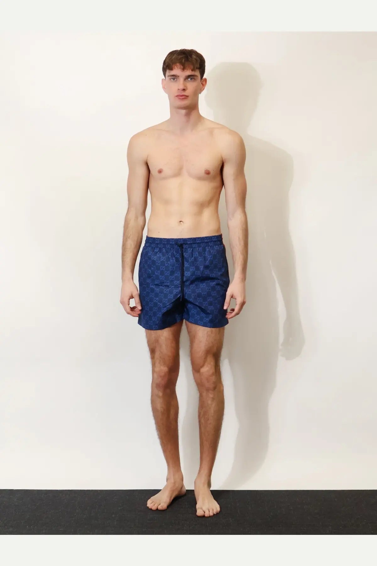 Blue Gucci men’s GG nylon swim trunks featuring a repeating monogram pattern for stylish beachwear
