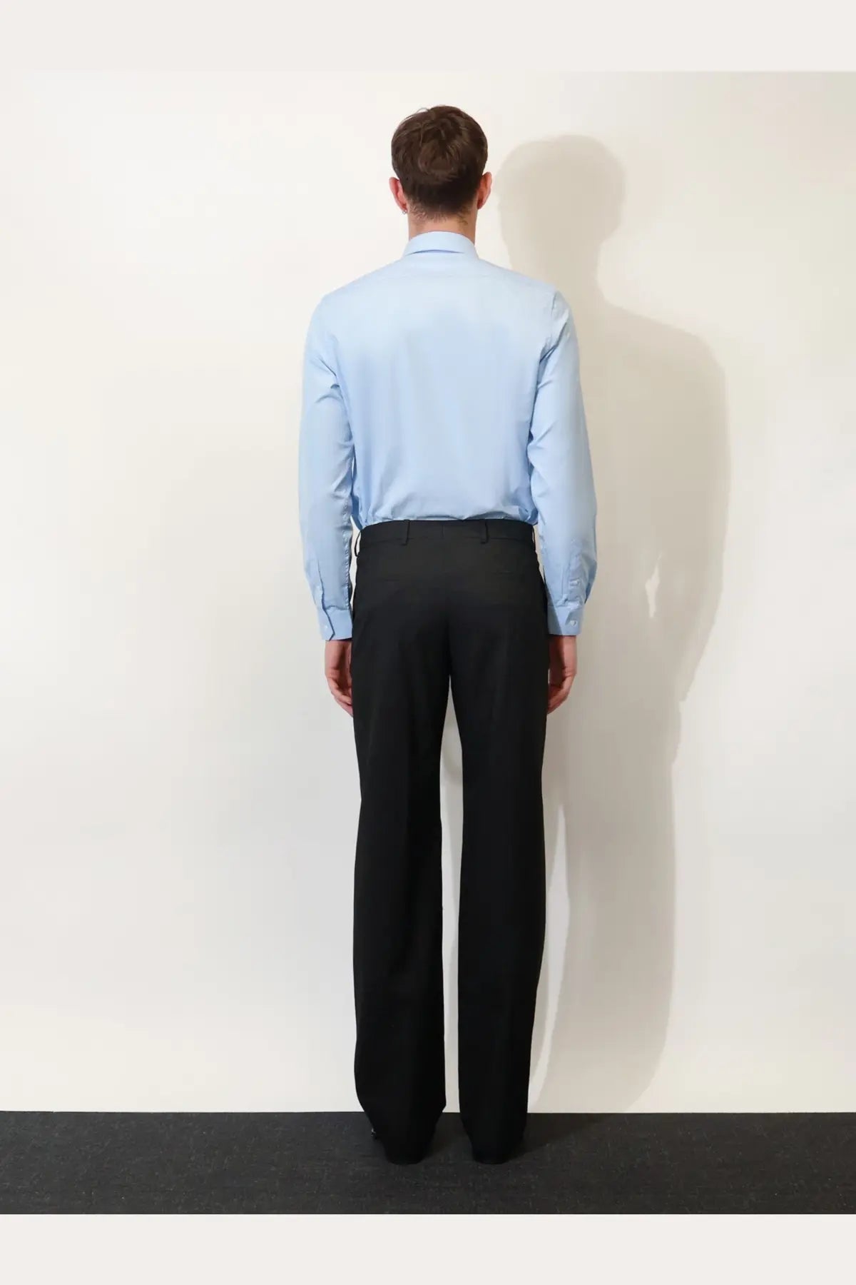 A man wearing Gucci men’s black GG wool blend formal trousers paired with a light blue long-sleeved dress shirt