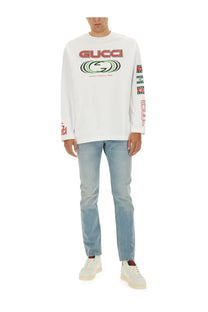 Gucci men’s white jersey long sleeve graphic tee with bold red and green logo print on chest and sleeves