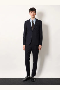 A man wearing a dark navy pinstripe wool blazer with matching trousers and a light blue dress shirt by Gucci