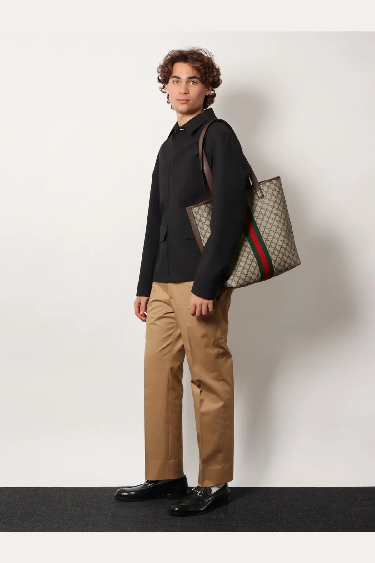 Beige and brown gucci tote bag with red and green striped shoulder strap shown with gucci men’s wool shirt jacket grey