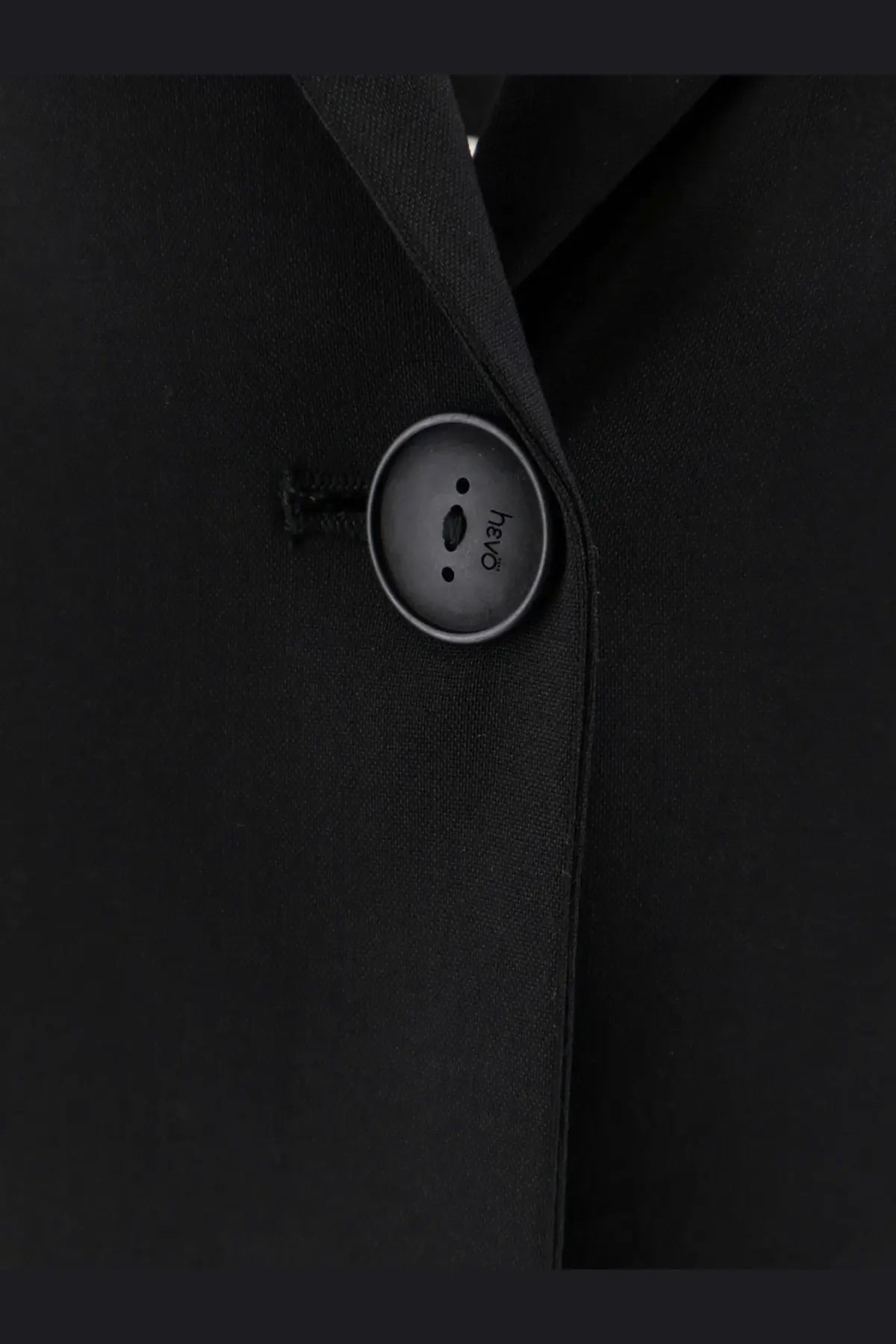 A sleek matte black button with a silver rim on hevò womens frigole virgin sheeps wool black suit