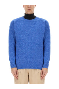 Howlin men’s wool jersey blue heathered wool sweater with ribbed cuffs and hem worn over black turtleneck