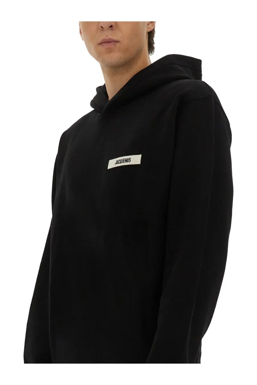 Jacquemus men’s black hooded sweatshirt with white rectangular label and black text on the chest