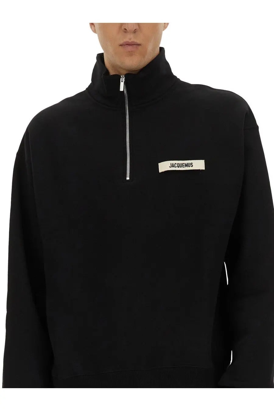 Jacquemus men’s black half-zip sweatshirt with white label on chest featuring a zippered turtleneck design
