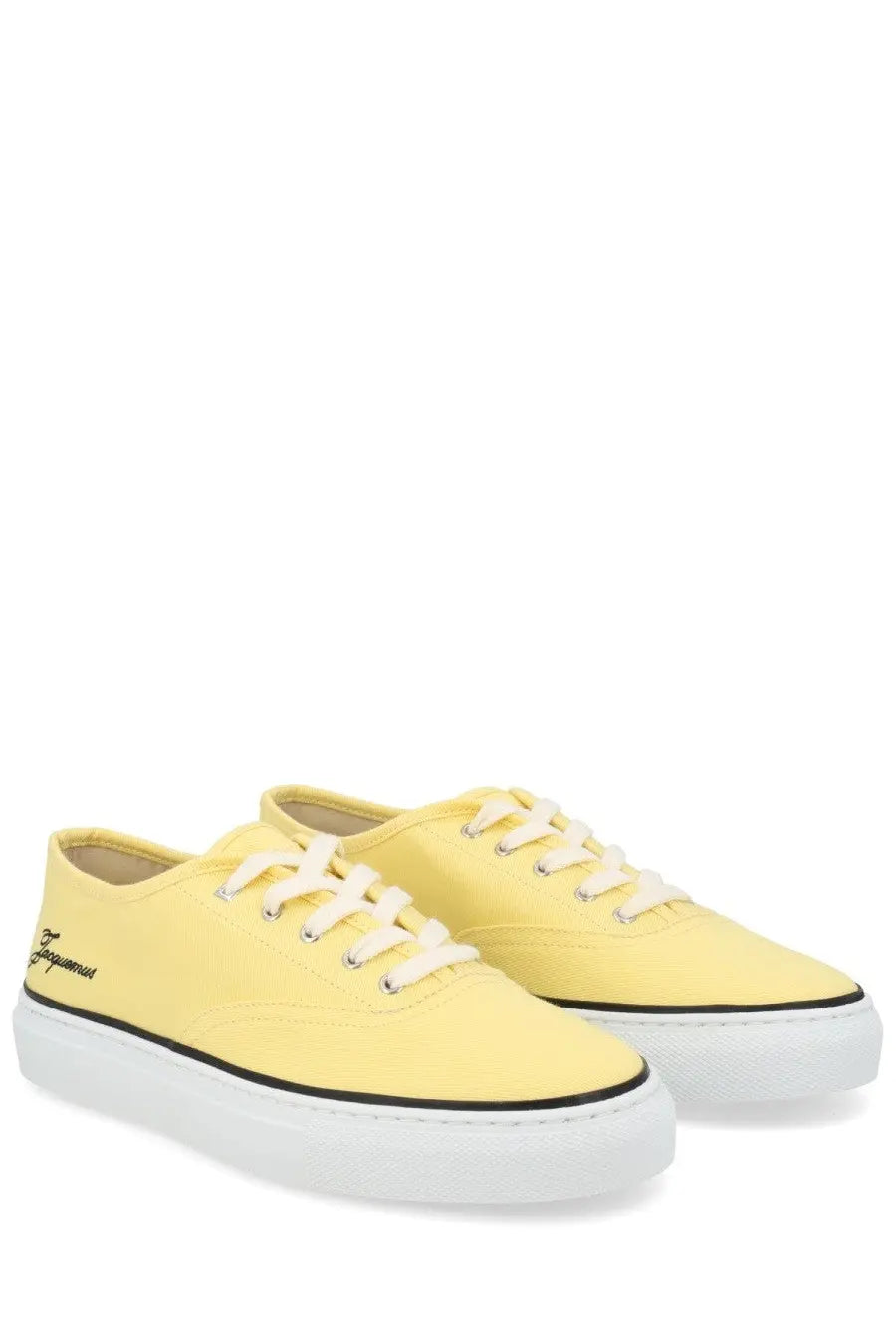 Pair of jacquemus women’s pale yellow canvas sneakers with white laces and black stripe along the sole