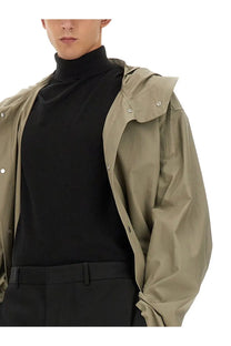Beige trench coat with silver toned buttons and structured collar shown from the back, styled with jil sander men’s parka green