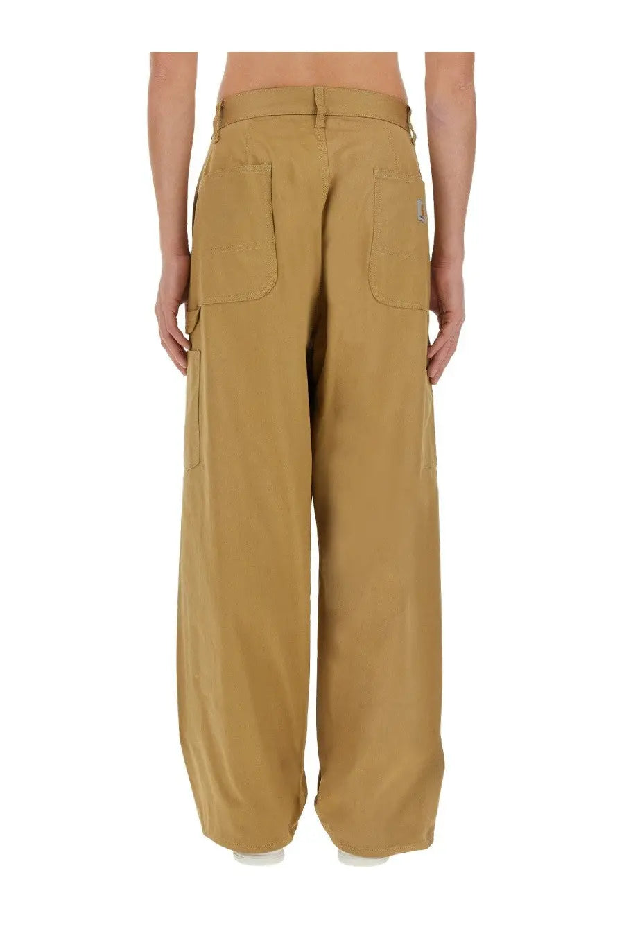 Back side of tan junya watanabe man cargo pants with multiple pockets and brand patch on the right hip
