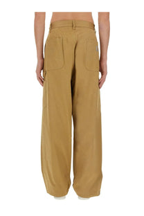 Back side of tan junya watanabe man cargo pants with multiple pockets and brand patch on the right hip