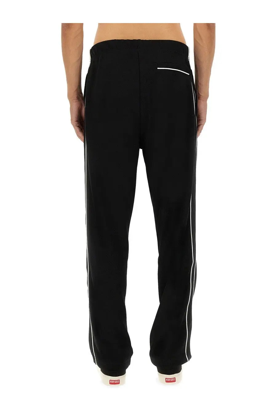 Kenzo men’s black track pants with white side stripes and a small red logo on the back waistband shown from behind