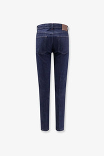 Kiton men’s cotton blend dark indigo slim fit jeans with brown leather brand patch at the waistband back view