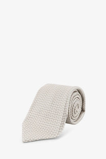 A neatly rolled kiton men’s silk tie in beige with a subtle woven texture and multicolor accents