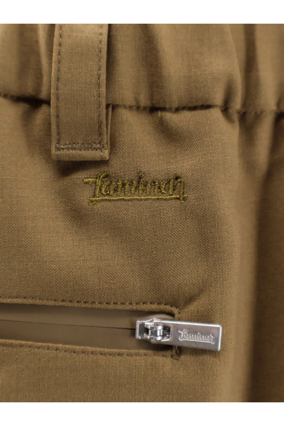 Tan khaki canvas pants with subtle embroidered tannhauser logo and silver zipper pull in laminar mens wool blend bermuda shorts green
