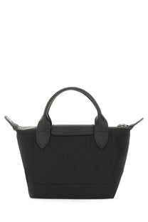 Black Longchamp le pliage mini handbag with structured silhouette and signature top handle in nylon and leather