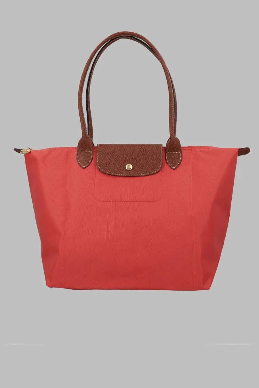 Vibrant coral-red Longchamp Le Pliage tote bag with brown leather handles and flap closure for women