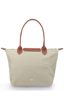 Beige Longchamp Le Pliage tote bag with brown leather handles and trim shown from the front in medium grey style